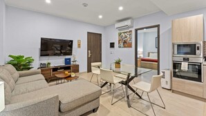 Un salon moderne comprenant un canapé, un téléviseur et un coin repas avec des chaises et une table.