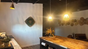 Une cuisine moderne avec un plan de travail en bois, des luminaires suspendus et un élément décoratif mural.