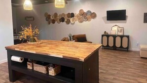 Un salon moderne avec une table basse en bois, des luminaires suspendus, un mur décoré d’assiettes rondes et un téléviseur fixé au mur.