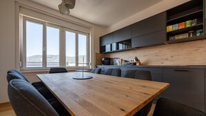 A modern kitchen with a wooden table and chairs, a large window with a view, and built-in cabinets. - Tamlivingcenterluxus4 Zimmer mit Smart Tvküche (Graz)