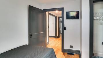 Habitación de hotel con una cama, un televisor en la pared y un perchero.