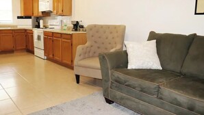 Una cuina moderna amb armaris de fusta, una armchair beix i un sofà verd.