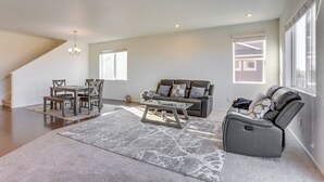 Un salón amplio con comedor, un sofá gris y un sillón reclinable.
