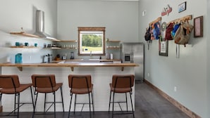 A modern kitchen with a central island, bar stools, and a view of the outdoors. - New Barndo/ATV Trailer Park/Outdoor Shower/HotTub (Stanton)