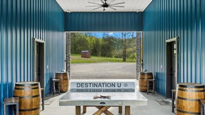 A room with a view of a green landscape, a table with barrels, and a sign reading "DESTINATION U". - New Barndo/ATV Trailer Park/Outdoor Shower/HotTub (Stanton)