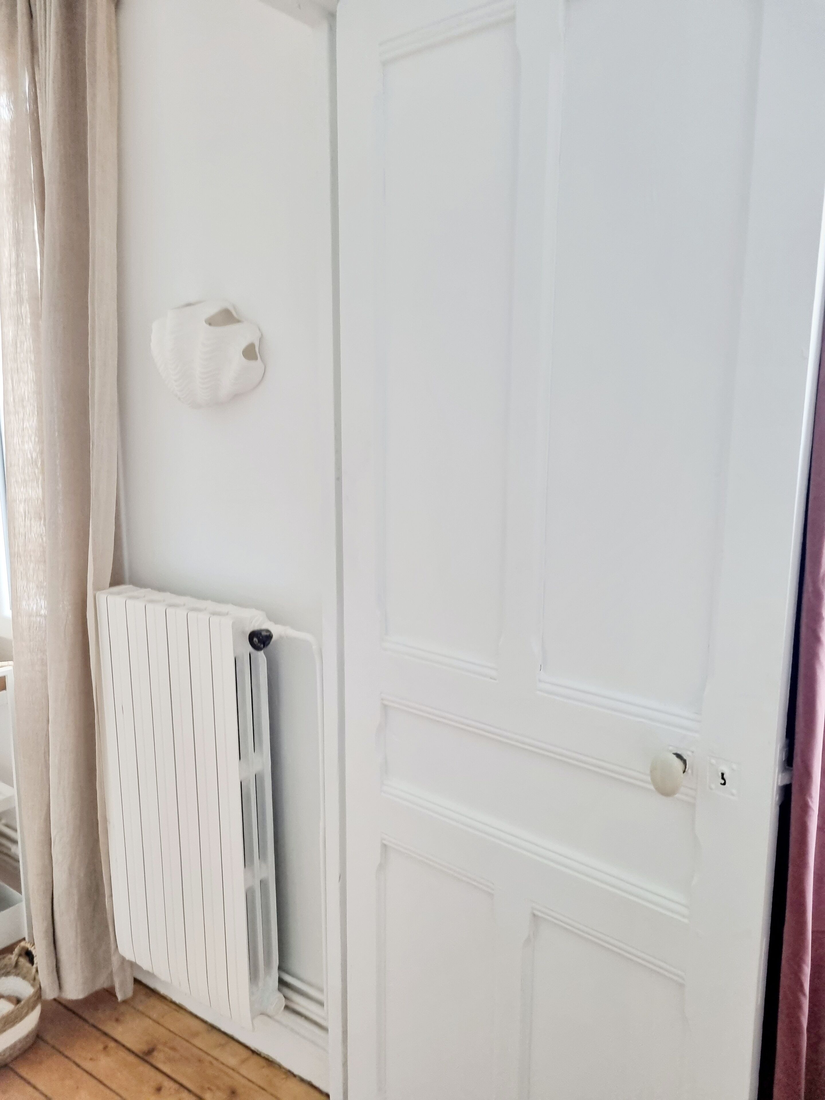A white door with a radiator and a wall-mounted light fixture.