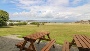 A picnic area with wooden benches and a paved walkway. - Cim Canol (Pwllheli)