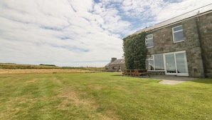A house with a large grassy yard, a stone facade, and a tall tree in front. - Cim Canol (Pwllheli)