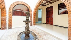 A courtyard with a stone fountain, brick arches, and a wooden door with the number 5.