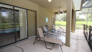 A covered patio area with lounge chairs, a ceiling fan, and a view of a swimming pool and lawn. - Mushu's Temple 122LP (Davenport)