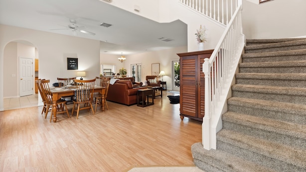 Un salón amplio con comedor, una escalera y vista a la cocina.