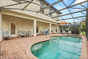 A covered swimming pool with lounge chairs and a patio area. - Paradise Retreat 200 HG (Clermont)