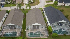 A residential area with three houses featuring large glass-enclosed swimming pools.