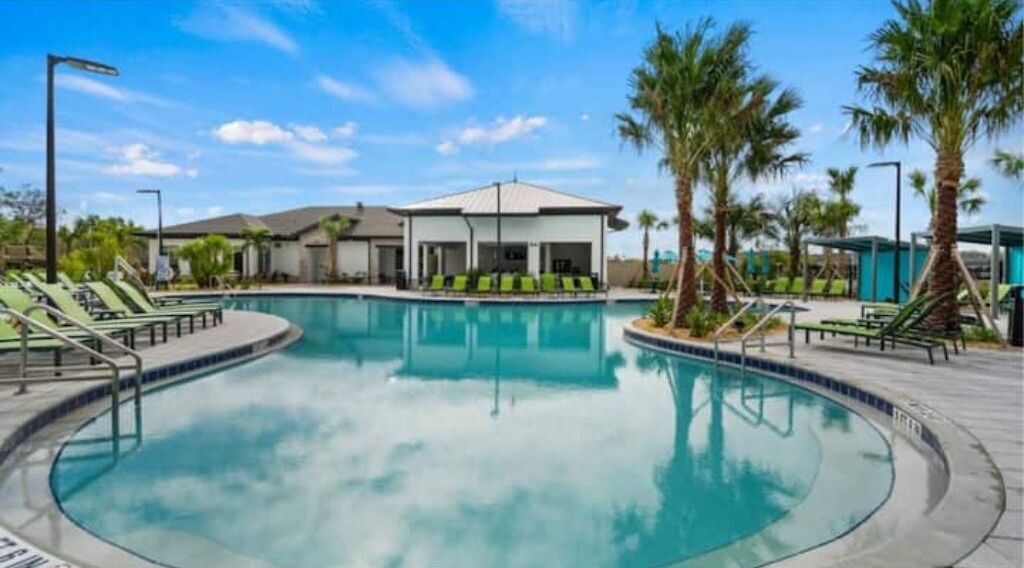 A swimming pool with lounge chairs and a covered seating area.