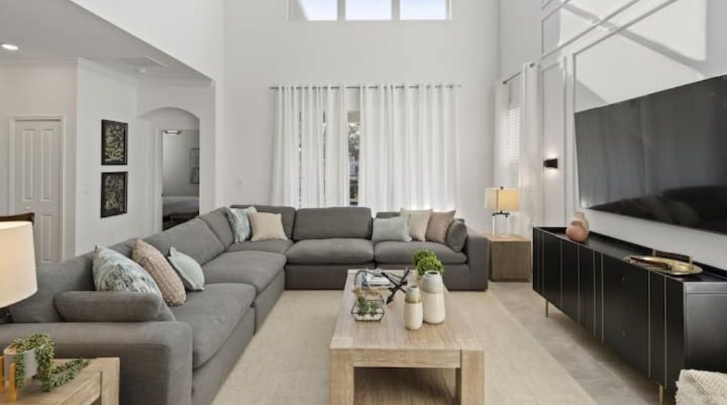 A modern living room with a sectional sofa, a coffee table, and a TV.