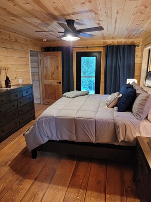 Un dormitorio con cama, cómoda, ventilador de techo y puerta que da a un balcón.