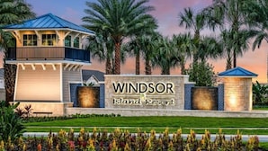 En entré till ett semesterhotell med en skylt som lyder ”Windsor Island Resort”, omgiven av palmer och en välskött gräsmatta.