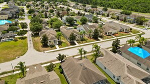 An aerial view of a residential area with houses, streets, and green spaces. - Pool Home in Resort Community (Kissimmee)