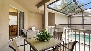 A balcony with a table, chairs, a potted plant, and a pool. - Pool Home in Resort Community (Kissimmee)