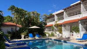 A pool area with blue lounge chairs, a small pool, and a building with a red-tiled roof. - Fabulous, spacious condo with pool, 5 mins from Mullins Beach. (Mullins)
