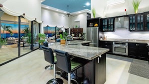 Una cocina moderna con una isla central, armarios oscuros y un ventilador de techo.