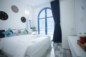 A modern hotel room with a large bed, a small bedside table, a mirror, and a window with blue shutters. - TNJ TASMANIA HOTEL (Da Nang)