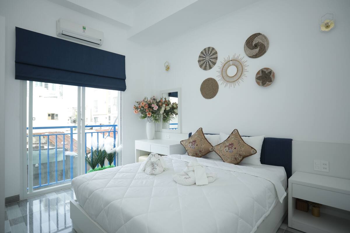 A hotel room with a large bed, a white nightstand, a mirror, and wall decor.