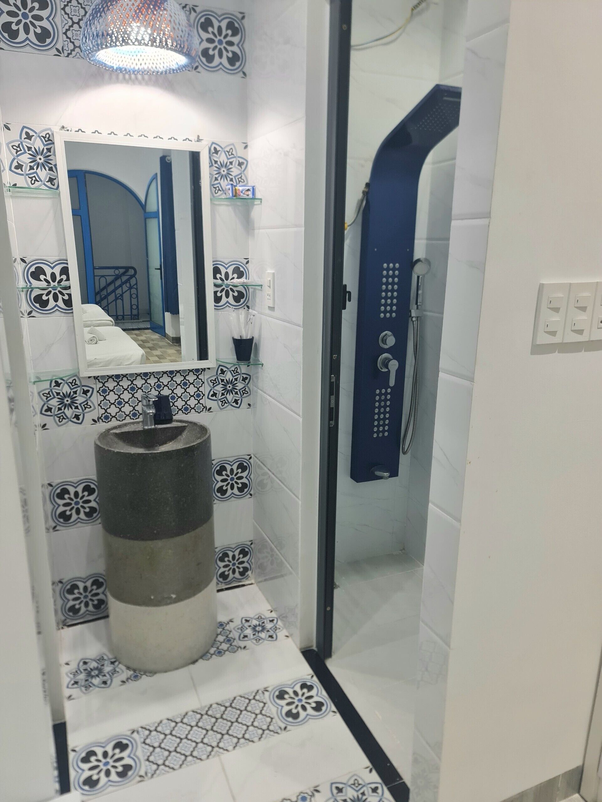 A bathroom with a shower, a sink with a decorative basin, a mirror, and patterned tiles.