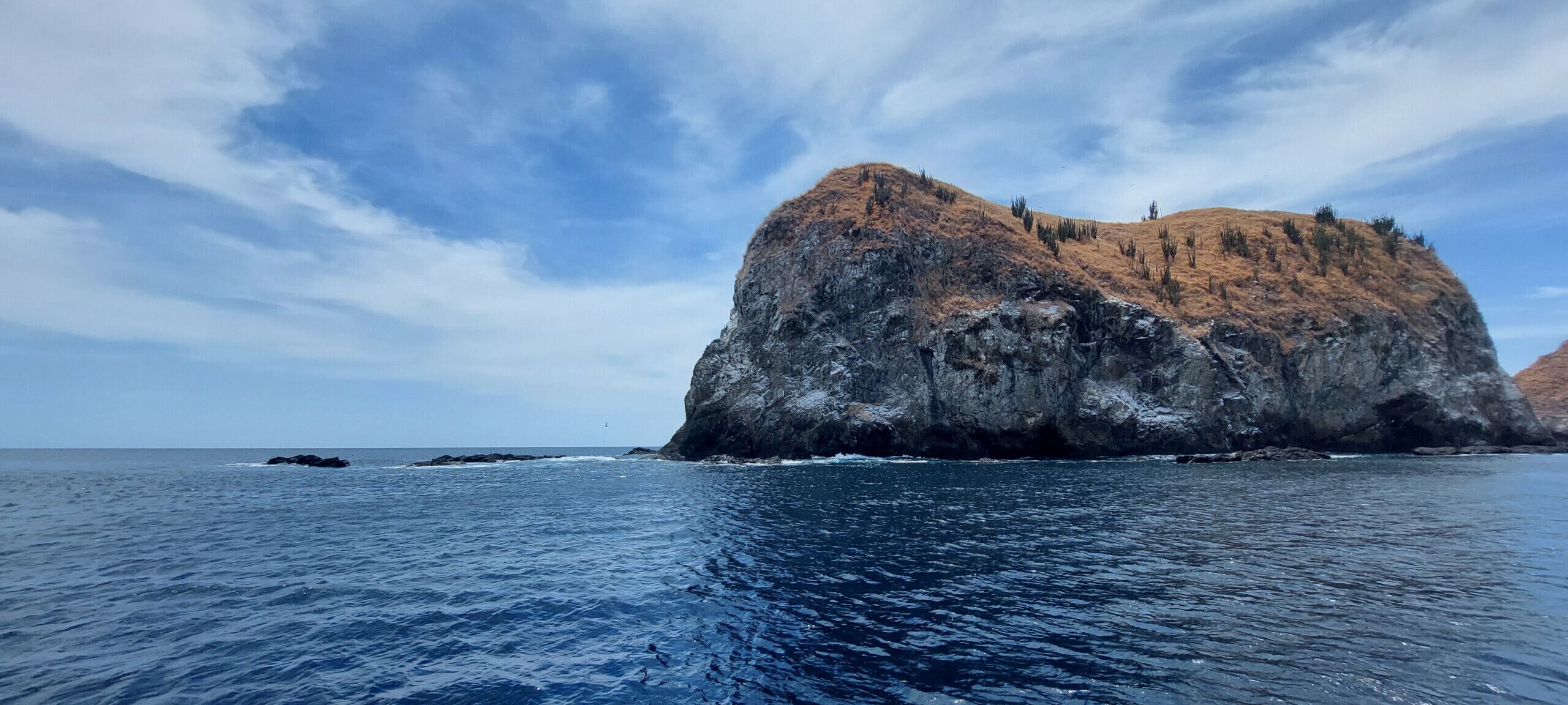 A large rock formation by the sea with clear skies.