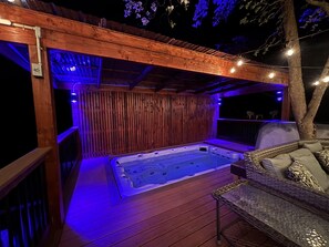 Eine Holzterrasse mit Whirlpool, umgeben von Holzwänden und Lichterketten.