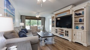 Una sala de estar con sofá, mesa de centro, televisor y muebles de almacenamiento.