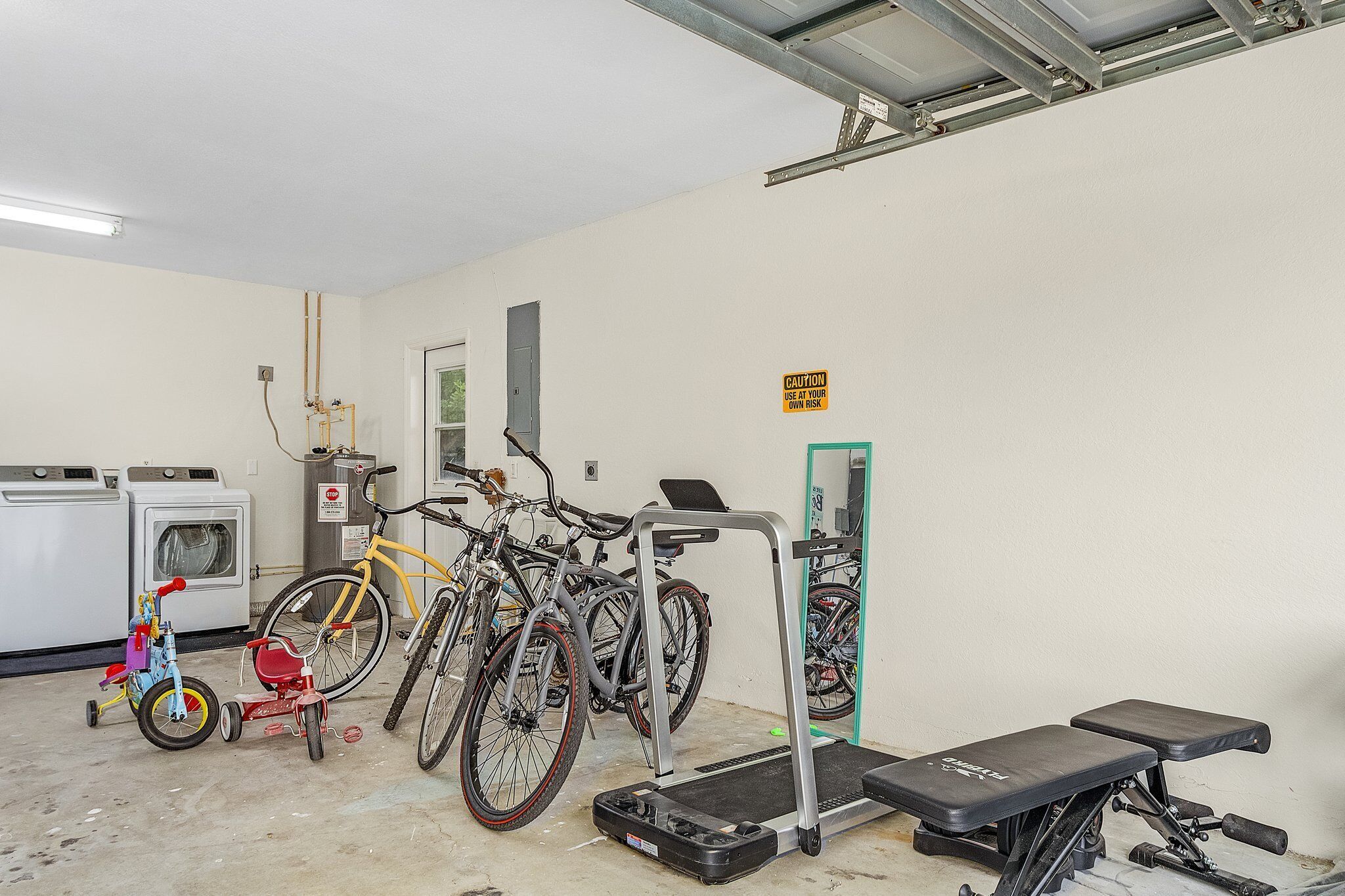 Un gimnasio con equipo de ejercicio, cinta de correr y bicicletas.