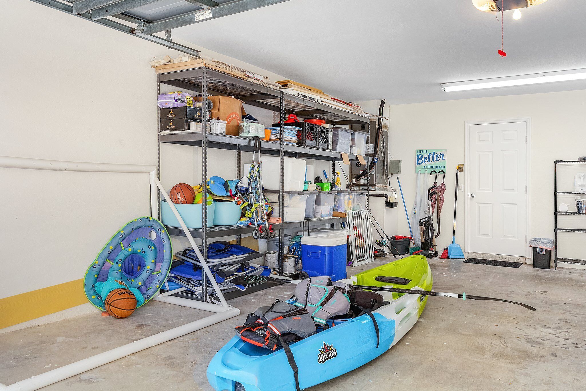 En garage med hylder fyldt med forskellige ting, en kajak og en redningskrans.