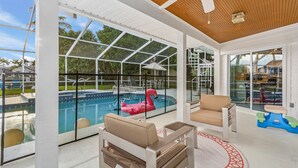 Un espacio al aire libre cubierto con piscina, sillas de descanso y ventilador de techo.