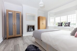 Une chambre à coucher avec un grand lit, une armoire, un miroir et une fenêtre donnant sur un beau paysage.
