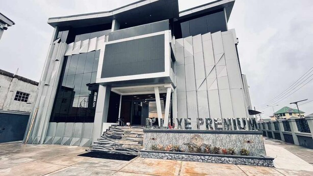 A modern building with a prominent entrance and a sign that reads "DIXE PREMIUM". - Dluxe Premium Hotel (Port Harcourt)