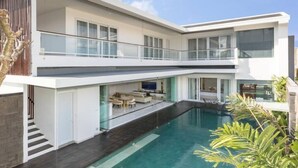 Ein modernes, zweistöckiges Haus mit Schwimmbad, Balkon und einer Treppe, die zum Obergeschoss führt.