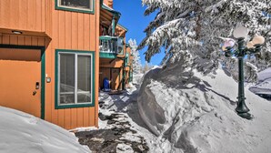 Un bâtiment en bois doté d’un balcon, des arbres couverts de neige et un sol enneigé.