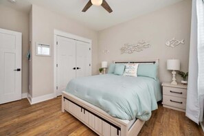 A bedroom with a bed, nightstands, a ceiling fan, a wardrobe, and decorative wall art. - 162 Barefoot  · Community Pool & Lake Access on Tims Ford (Winchester)