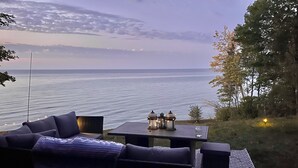 Un área de estar al aire libre con vista al mar, una mesa con faroles y una alfombra estampada.