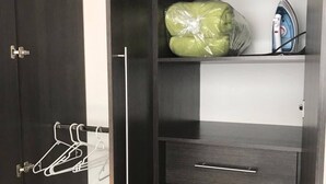 A wardrobe with a hanging rack, a shelf with a bag of laundry, and a drawer. - Studio apartment great location trendy area (Ciudad de Guatemala)