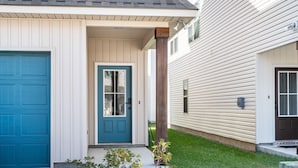 A two-story house with a blue front door, a white garage door, and a covered porch.