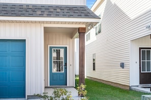 A two-story house with a blue front door, a white garage door, and a covered porch. - Tiger Stadium Oasis in Baton Rouge by LSU - CB1014 (Baton Rouge)