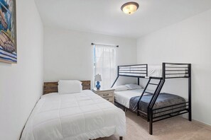 Ein Schlafzimmer mit Etagenbetten, einem Nachttisch, einer Lampe und einem Fenster mit Vorhängen.