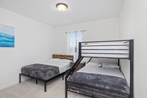 A bedroom with bunk beds, a wooden headboard, a window with curtains, and a painting on the wall. - Tiger Stadium Oasis in Baton Rouge by LSU - CB1014 (Baton Rouge)