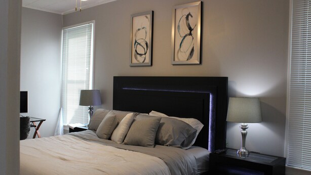 Une chambre à coucher avec un lit, des tables de chevet, une lampe et des œuvres d’art accrochées au mur.