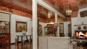 A cozy living room with a fireplace, wooden ceiling, and a comfortable sofa. - Chalé Terrazza  (Campos do Jordão)