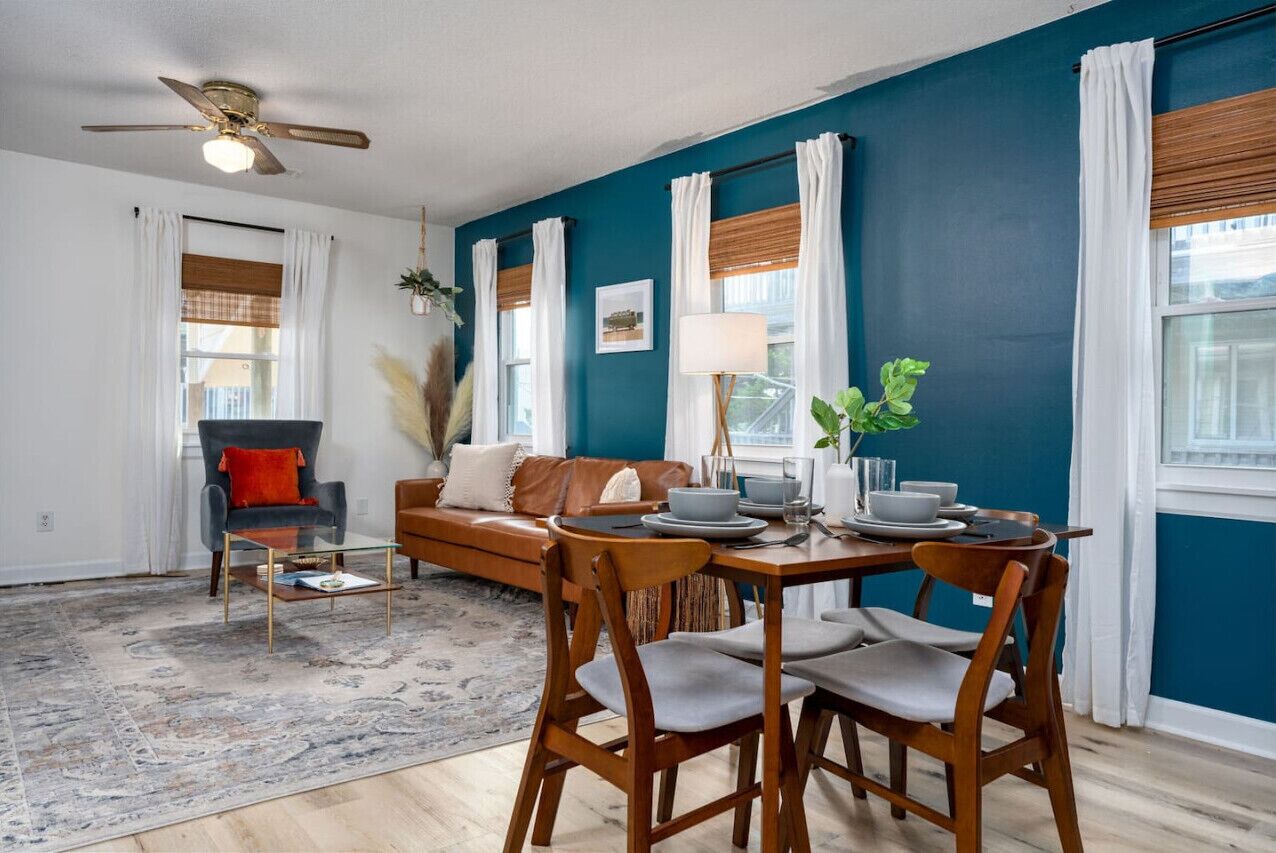 A dining area with a table set for four, a sofa, and a ceiling fan.