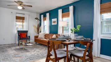 A dining area with a table set for four, a sofa, and a ceiling fan.
