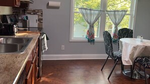 A kitchen with a sink, stove, and dining area with chairs and a table.
